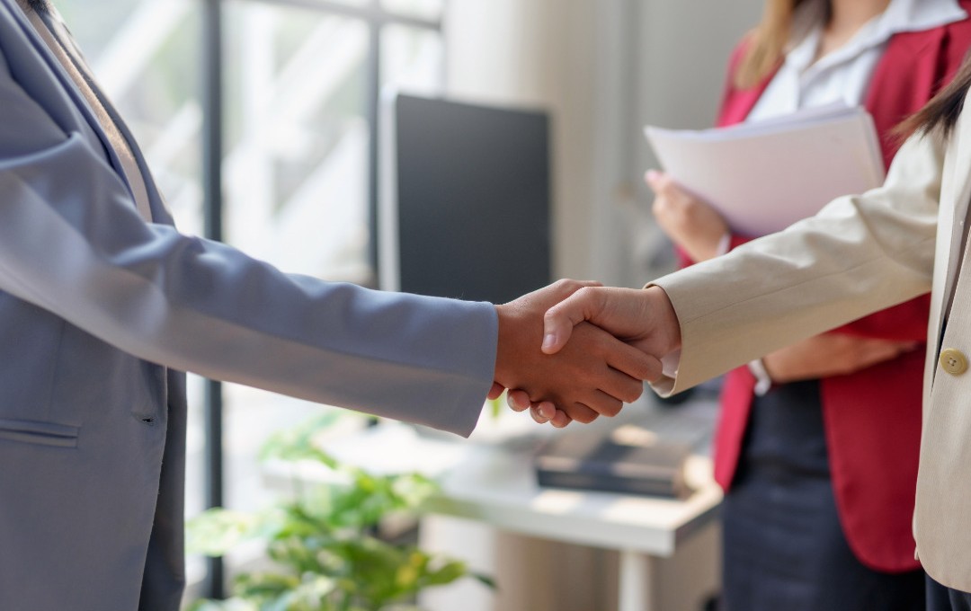 Zwei Mitarbeitende geben sich die Hand nach einer erfolgreichen Arbeitsplatzmediation.