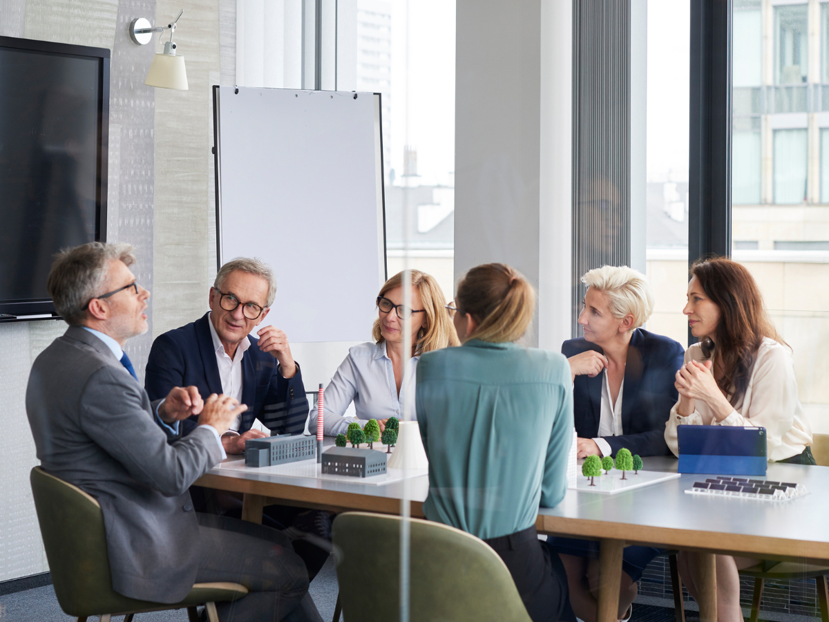 Drei Frauen und zwei Männer – alle unterschiedlichen Alters – sitzen in einem Besprechungsraum zusammen und diskutieren.