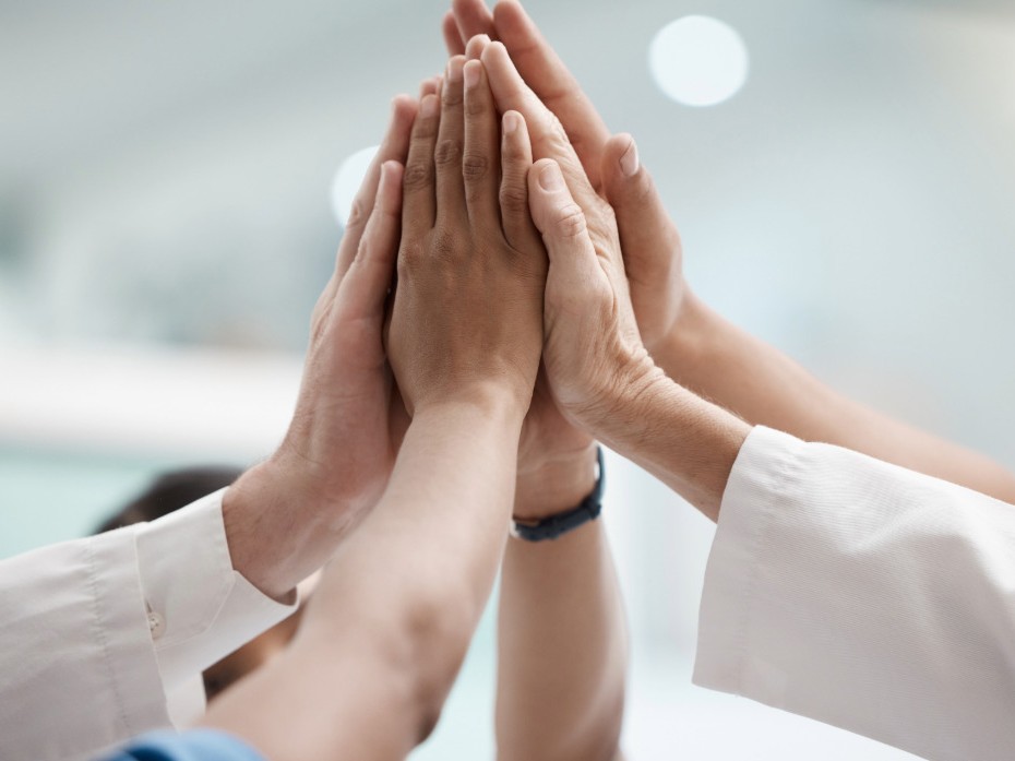 Mehrere Hände sind erhoben und zusammengehalten - steht für Wir-Gefühl und Teamerfolg