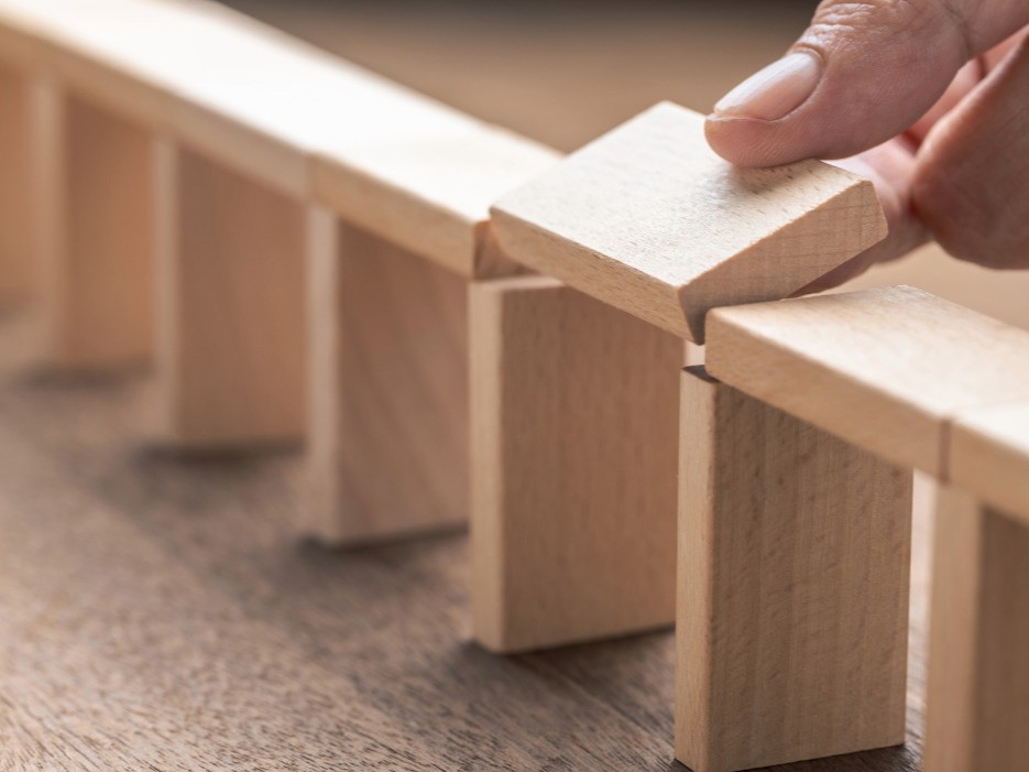 Mit Holzbausteinen wurde eine Brücke gebaut. Der letzte Stein wird gerade eingefügt.