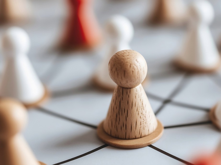 Holzfiguren, die miteinander durch Linien verbunden sind - steht für Teamzusammenhalt und Teamentwicklung