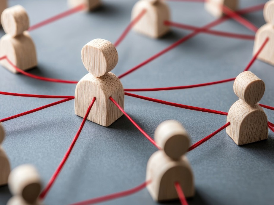 Holzfiguren sind durch Fäden miteinander in Verbindung - steht für eine Team, das durch Teamsupervision zu Zusammenhalt und Verbindung zurückgefunden hat.